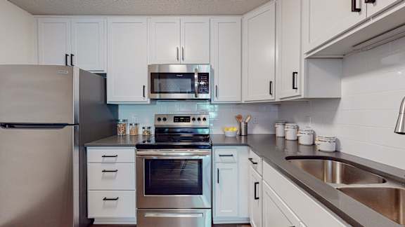 A kitchen with a refrigerator, oven, and microwave.