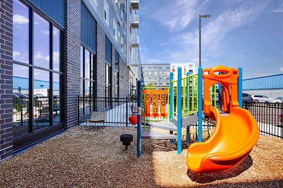 A playground with a bright orange slide in front of a building at Soul Apartments, Minnesota