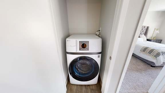 A white front load washing machine in a small room.