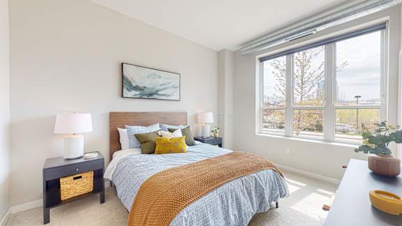 A bedroom with a bed, nightstands, and a window overlooking a field.