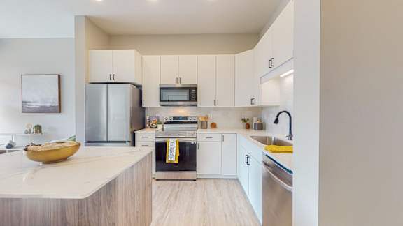 A modern kitchen with a refrigerator, microwave, oven, and sink.