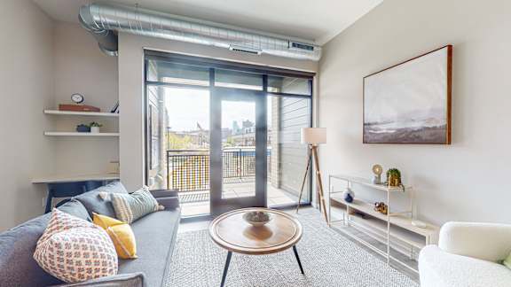 A living room with a grey couch, a wooden table, and a painting on the wall.
