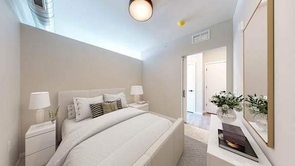 A bedroom with a large bed and a small table with a plant on it.