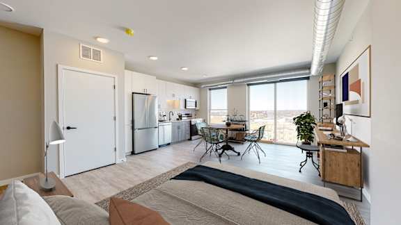A well-lit, modern living room with a dining area and kitchen in the background.