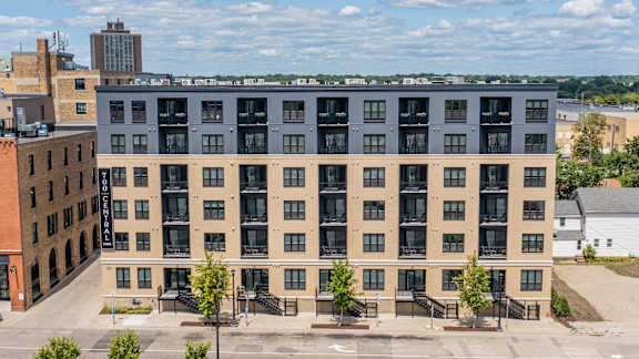 A large building with many windows is in the foreground with a clear sky in the background.