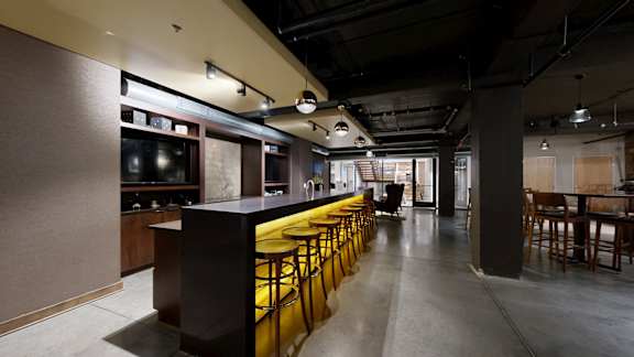 A long bar with stools is in the middle of a room.