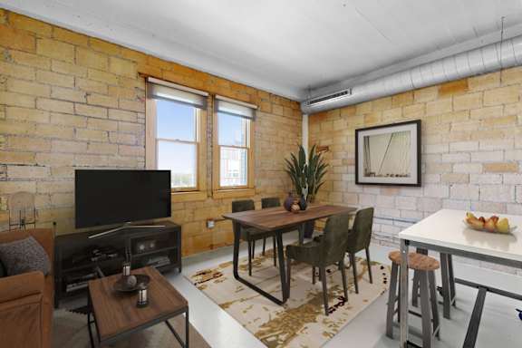 A living room with a brick wall and a flat screen TV.