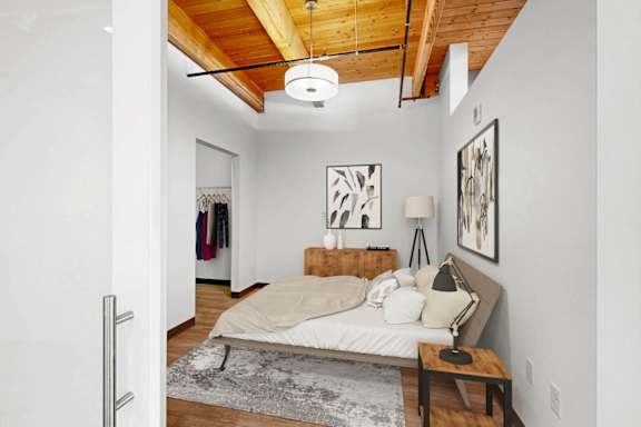 A bedroom with a bed, a bench, and pictures on the wall.