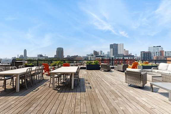 A wooden deck with chairs and tables overlooking a city skyline.