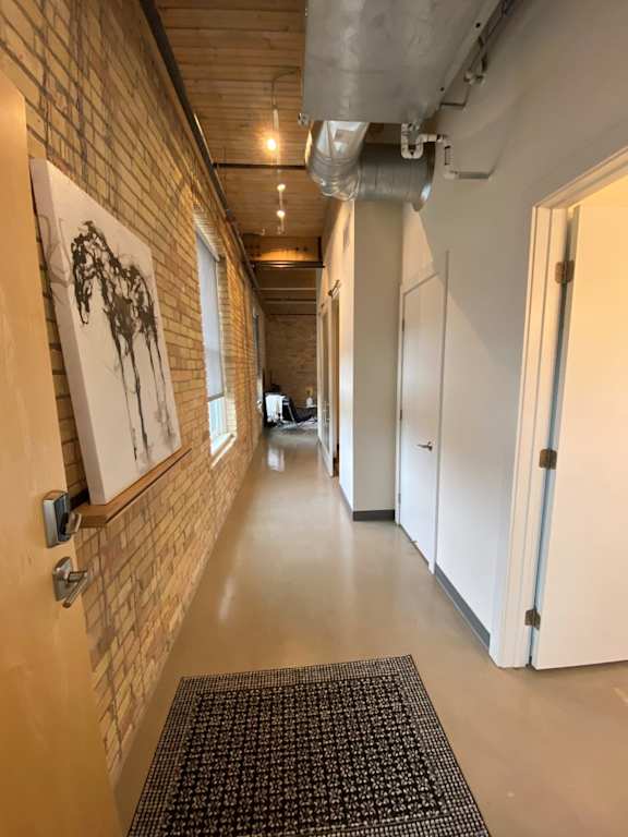 A hallway with a brick wall and a black and white patterned rug.