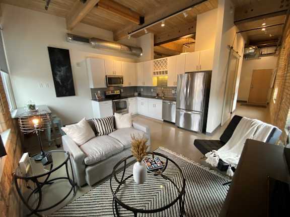 A modern living room with a black and white striped rug and a glass coffee table.