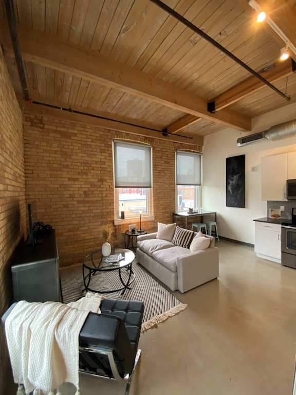 A living room with a couch, chair, and a table with a blanket on it.
