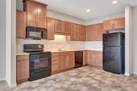 A kitchen with wooden cabinets and black appliances at Soul Apartments, St. Paul, MN 55107