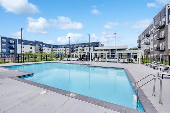 A large outdoor swimming pool with a blue water surface and a metal ladder on the right side.