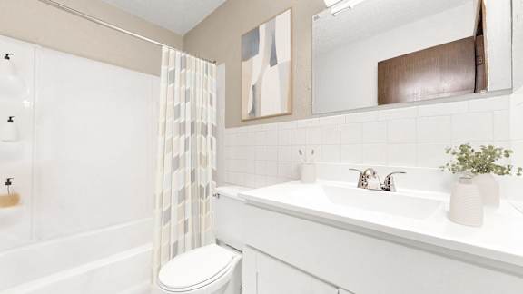A white bathroom with a toilet, sink, and shower.