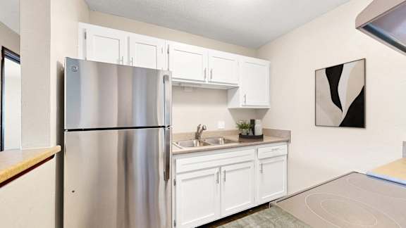 A kitchen with white cabinets and a stainless steel refrigerator.