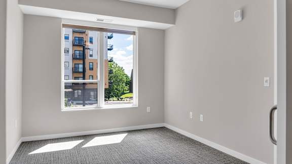 A room with a large window overlooking a street with buildings.