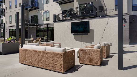 Two brown wicker sofas are placed on a patio in front of a building.
