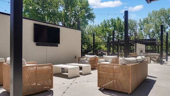 A patio area with wicker furniture and a television on a wall.