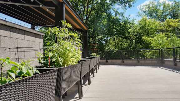 A concrete patio with a black metal railing and a wall with a brown roof.