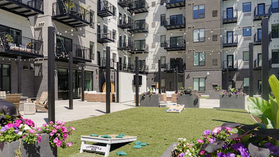 A construction site is in the middle of a grassy area with apartment buildings in the background.