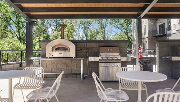 A patio with a table, chairs, and a pizza oven.