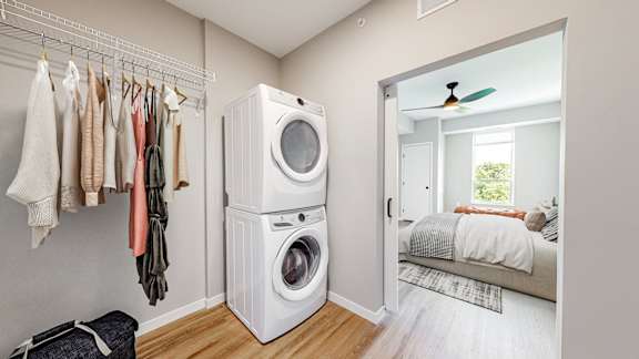 A laundry room with a washer and dryer stacked on top of each other at Ardor on the Bluffs South Loop Residences Apartments, Bloomington, 55425