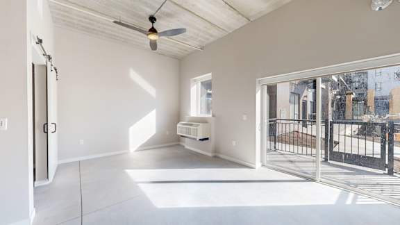 A spacious room with a ceiling fan and sliding glass doors. at Ardor on the Bluffs South Loop Residences Apartments, Bloomington, Minnessota