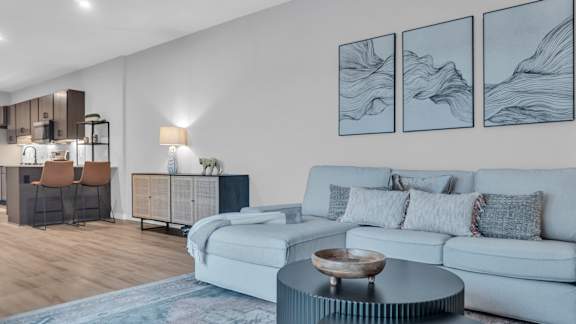 A modern living room with a white sofa, a wooden coffee table, and a cabinet with a glass door.