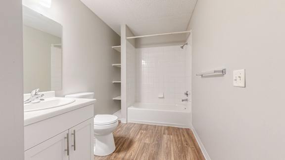 A white bathroom with a toilet, sink, and a walk-in shower.