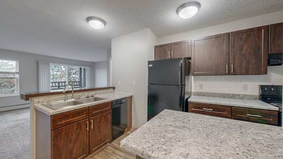 A kitchen with a refrigerator, sink, and cabinets.