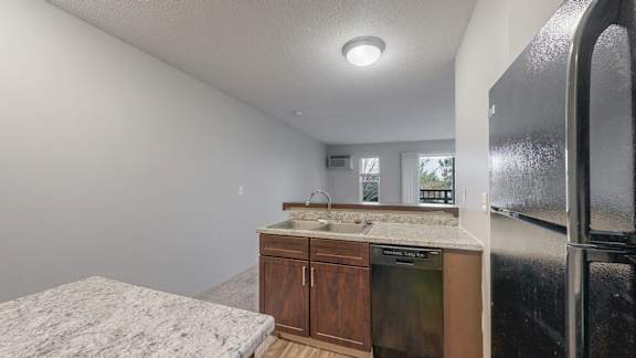 A kitchen with a sink, cabinets, and a refrigerator.