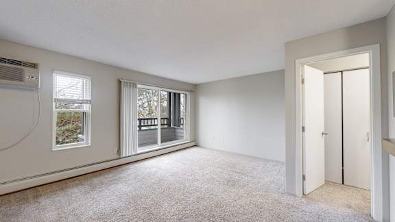 A room with a carpeted floor, a window, and a door.