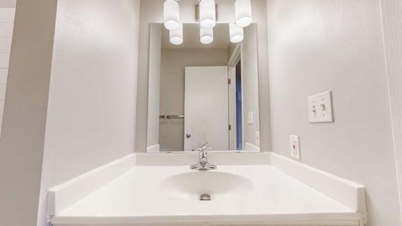 A white sink in a bathroom with a mirror above it.