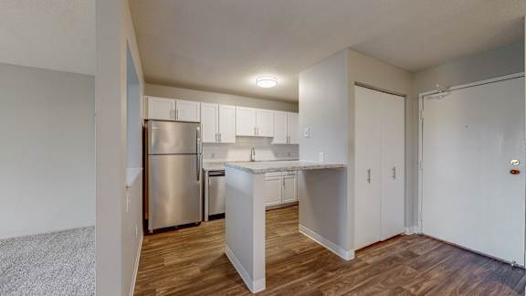 A kitchen with white cabinets and a stainless steel refrigerator.
