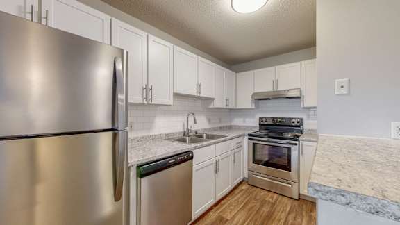 A kitchen with a stainless steel refrigerator and white cabinets.