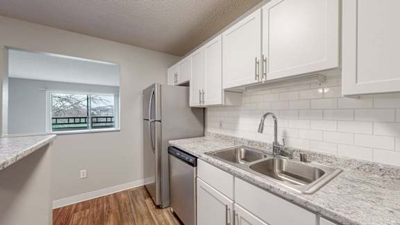 A kitchen with a refrigerator, dishwasher, and a sink.