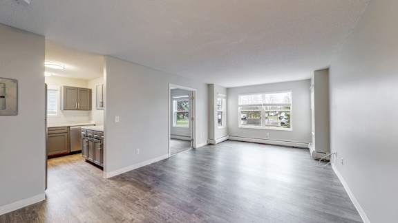 A spacious living room with hardwood floors and a view of the kitchen area.