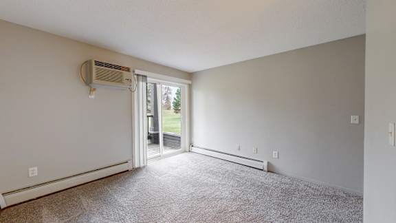 A room with a carpeted floor and a sliding glass door leading to a backyard.