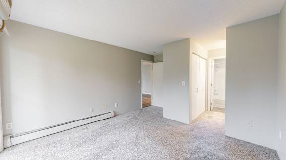 A spacious room with a carpeted floor and white walls.