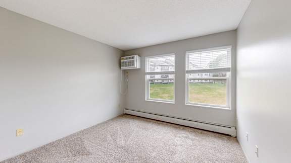 A room with a window and a carpet on the floor.