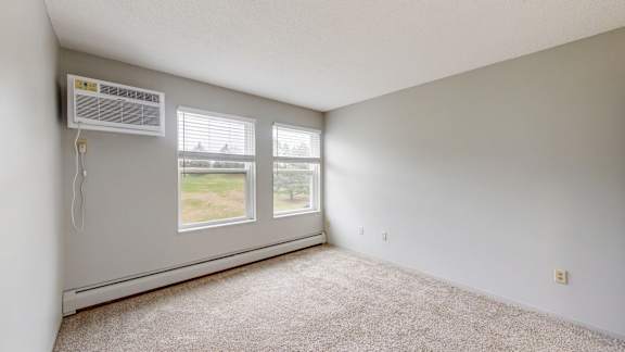 A room with a window and a wall-mounted air conditioner.