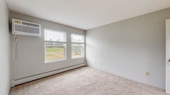 A room with a window and a carpeted floor.