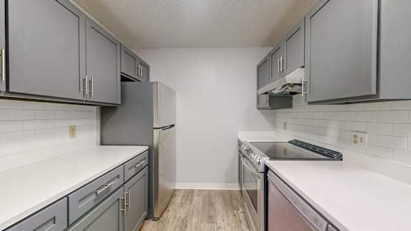A kitchen with white countertops and grey cabinets.