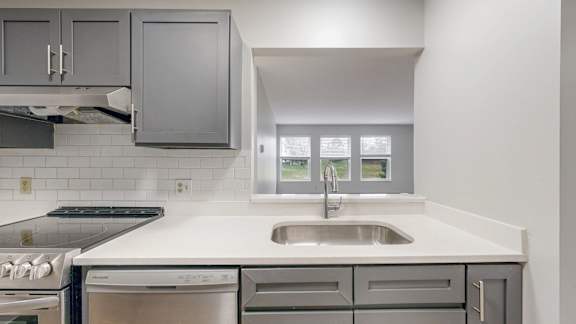 A modern kitchen with a stainless steel dishwasher and a white countertop.