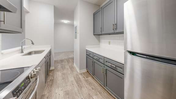 A modern kitchen with stainless steel appliances and wooden flooring.