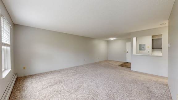 A spacious room with a carpeted floor and a window on the left side.