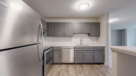 A modern kitchen with stainless steel appliances and wooden floors.