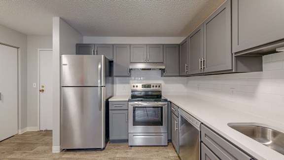 A modern kitchen with stainless steel appliances and grey cabinets.
