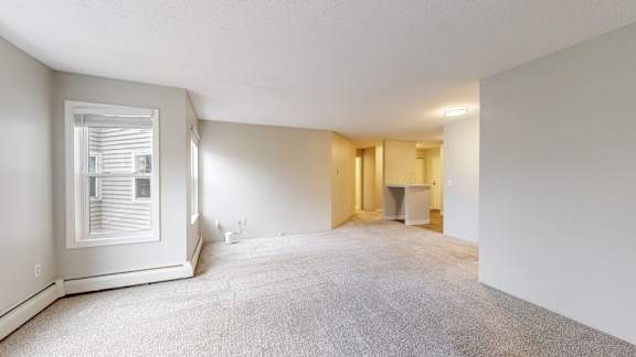 A room with a carpeted floor and a window with blinds.